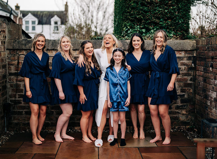 a group of people wearing dressing gowns and pyjamas standing next to a stone wall