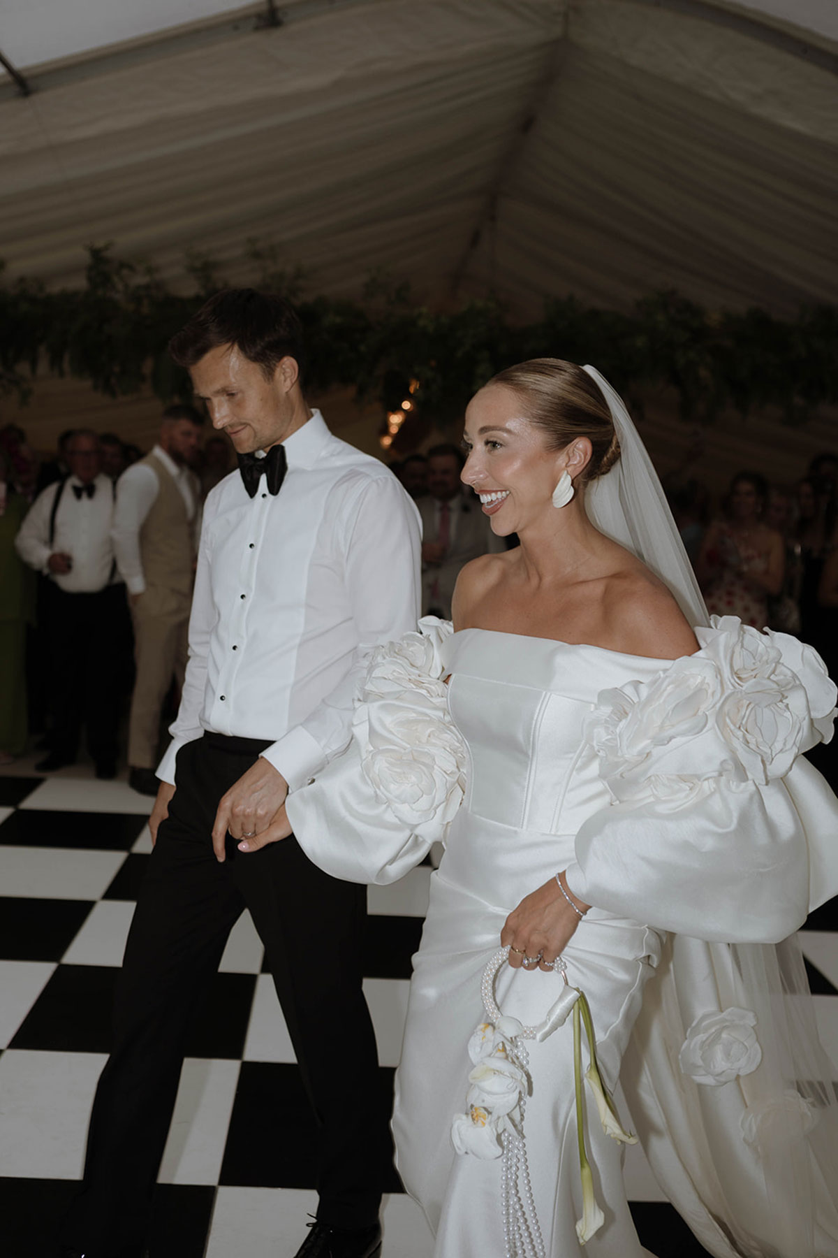 Newlyweds entering marquee wedding reception to cheering guests during stylish Ayrshire farm wedding