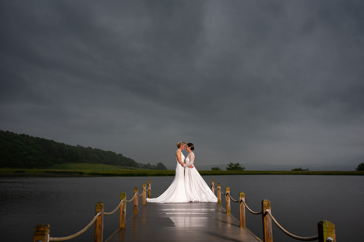 Two brides standing on the jetty overlooking the reservoir at The Vu in Bathgate
