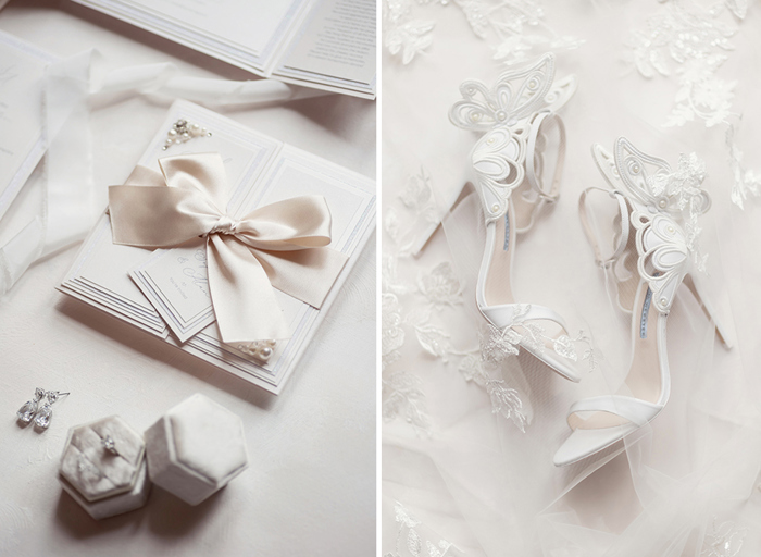 a wedding flat lay of white wedding stationery tied with a ribbon bow, a ring in a light grey velvet box and crystal drop earrings on left. A close up of Sophia Webster butterfly sandal heels and lace veil on right