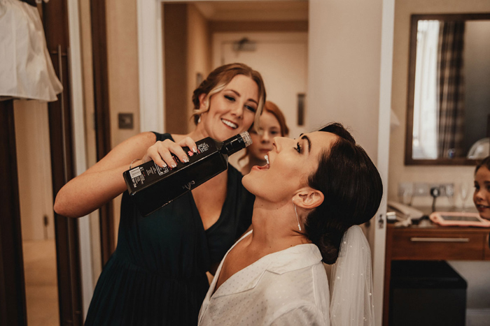 Bride has tequila rose poured in her mouth by bridesmaid