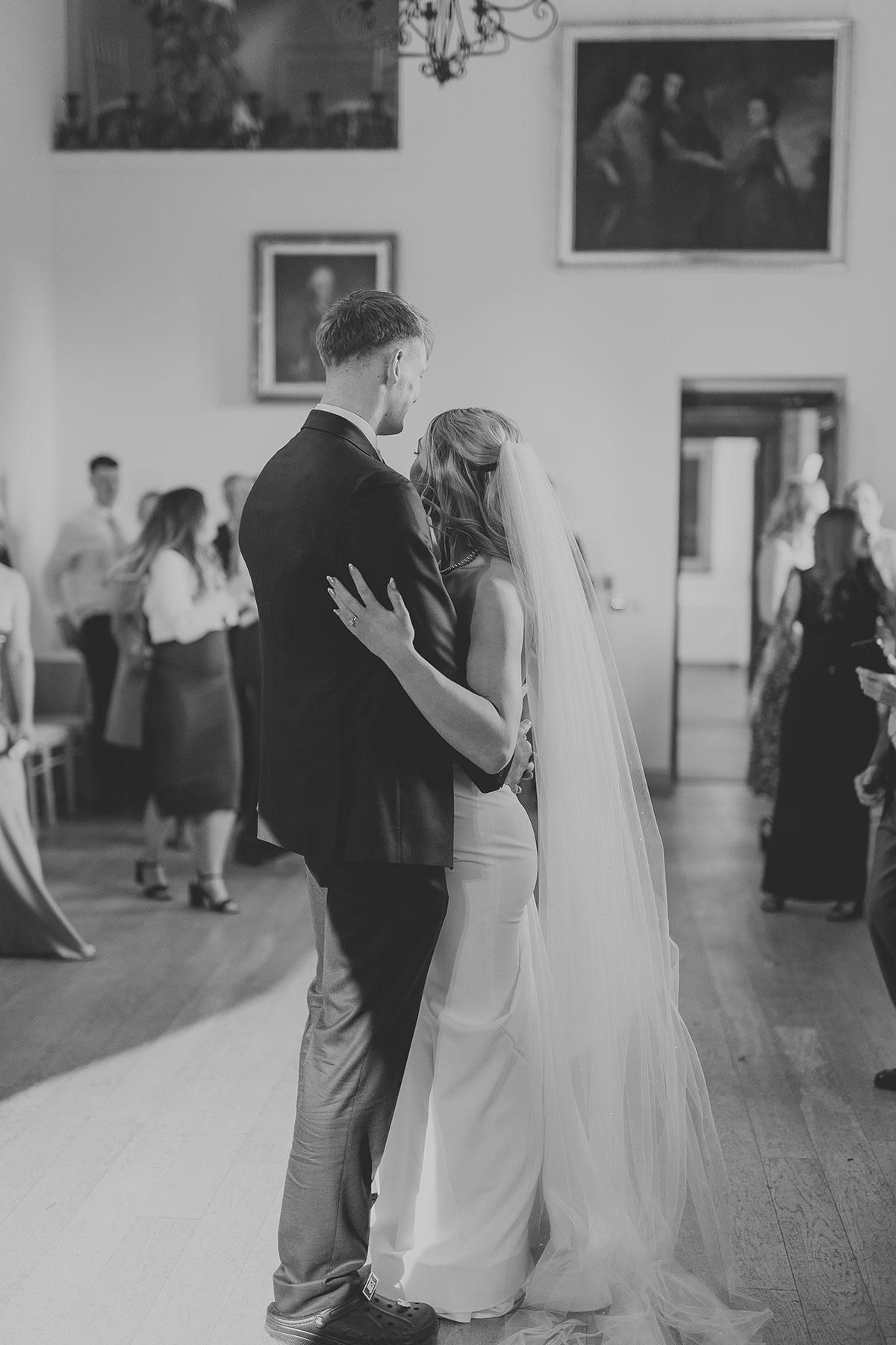 Black and white photo of bride and groom embracing on dancefloor during wedding reception