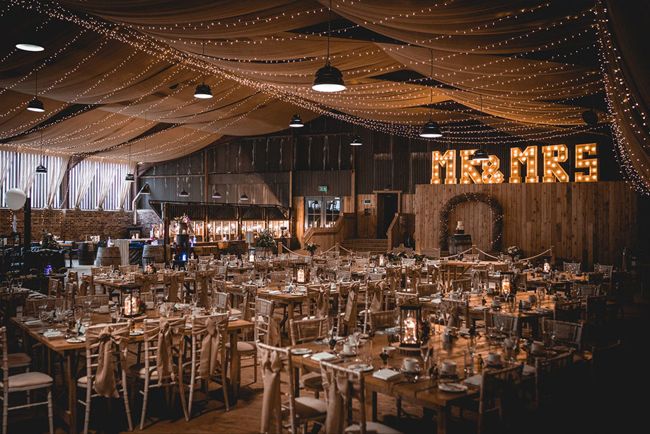 a room with a canopy of fairy lights and lots of wooden tables