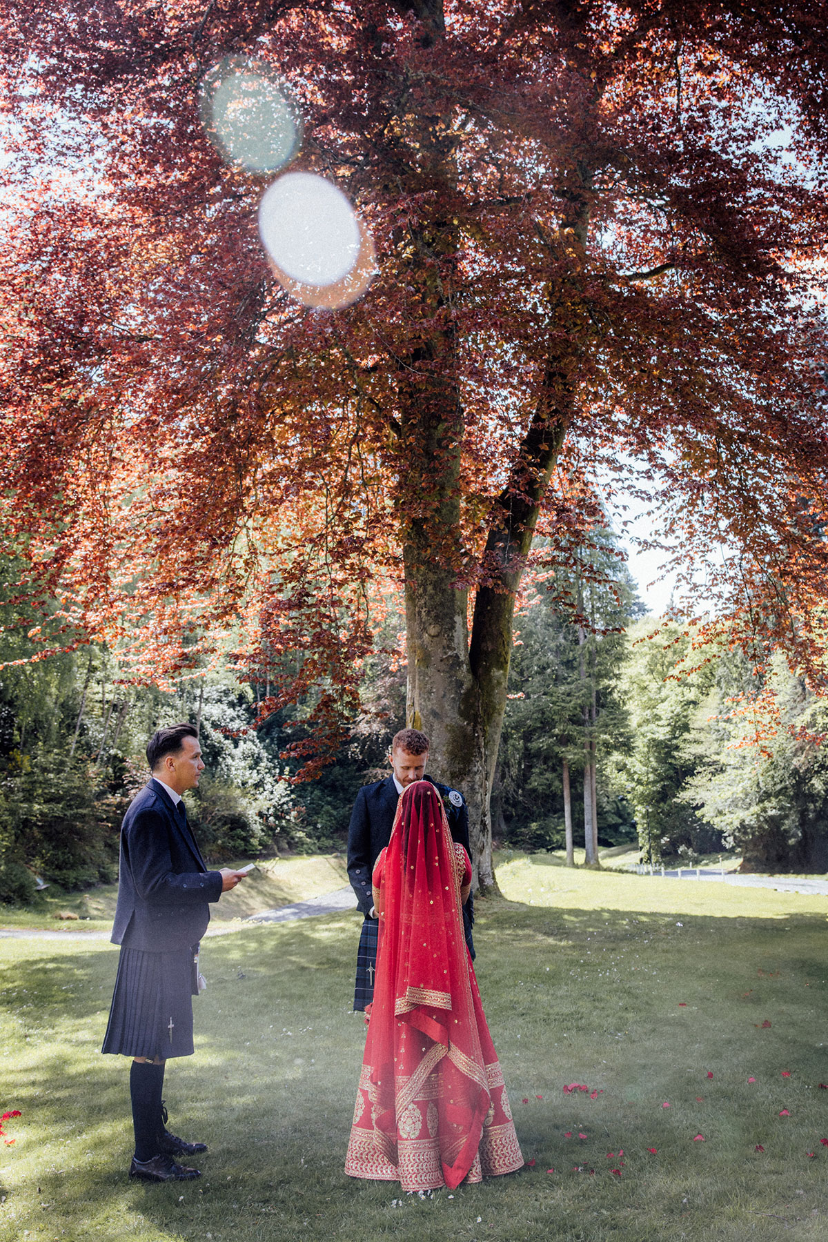 Bride and groom exchanging vows during an outdoor ceremony beneath a copper beech tree at Atholl Palace Hotel