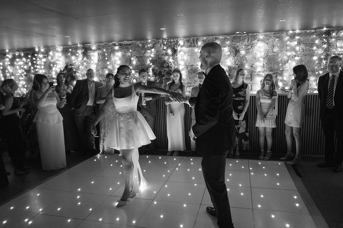 Bride and groom first dance at Glasgow wedding reception surrounded by guests and fairy lights