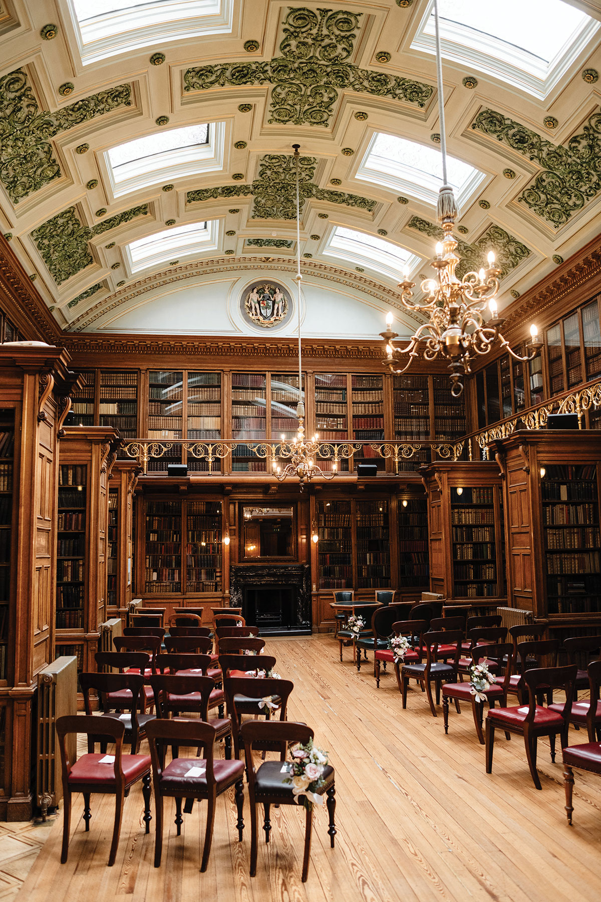 Ceremony chairs arranged in the historic library at the Royal College of Physicians of Edinburgh, with ornate bookcases, chandeliers and a vaulted ceiling overhead