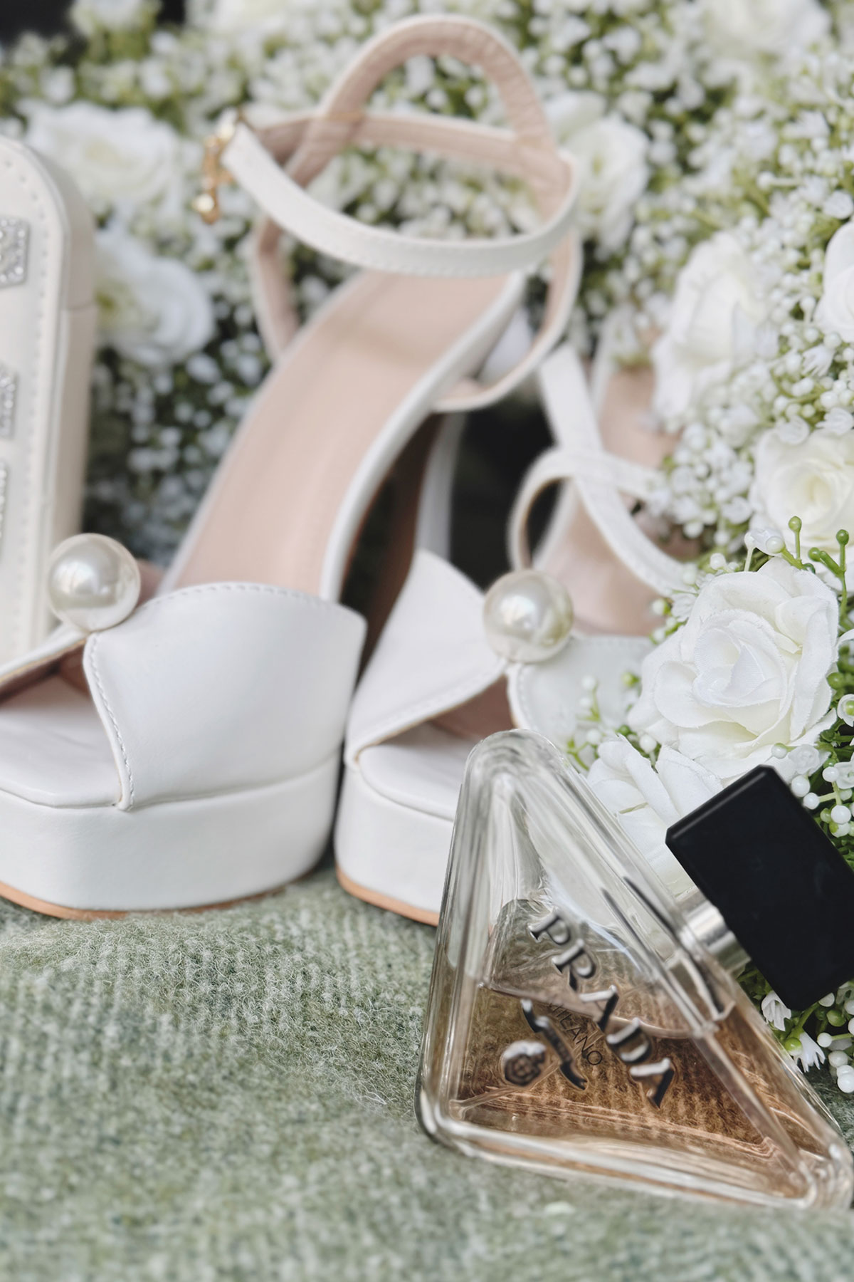 a close-up detail of white shoes and Prada perfume bottle