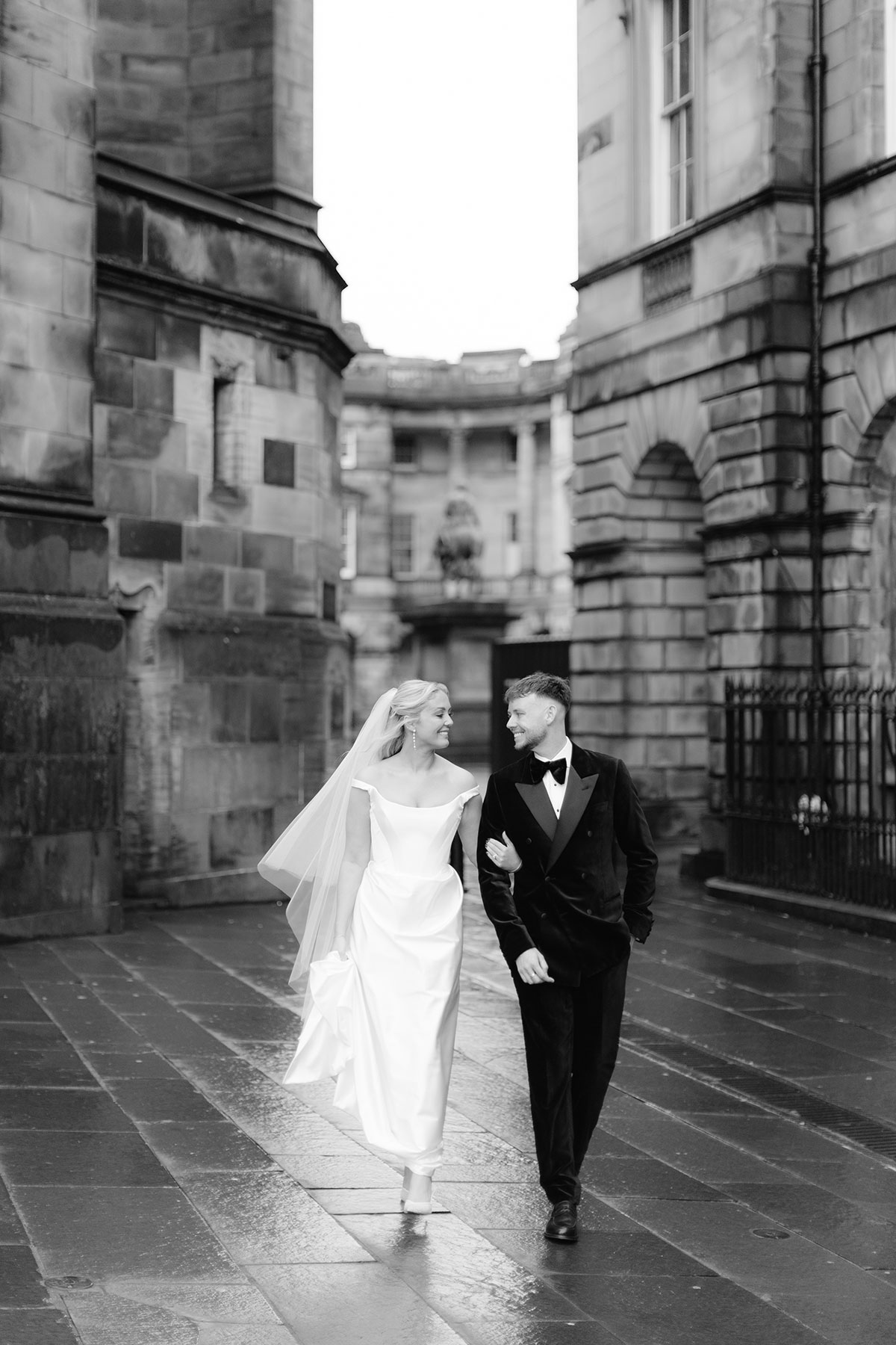 Bride and groom walking together through Parliament Square in Edinburgh on their wedding day