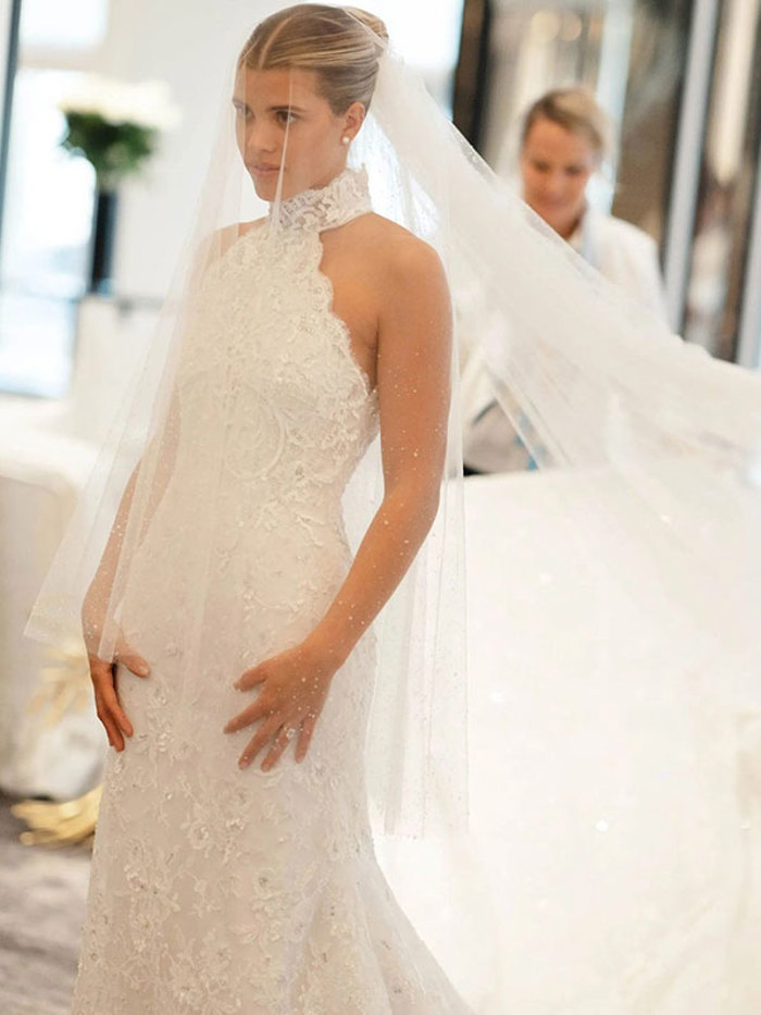 Sofia Richie looks in the mirror wearing an embellished halterneck wedding dress