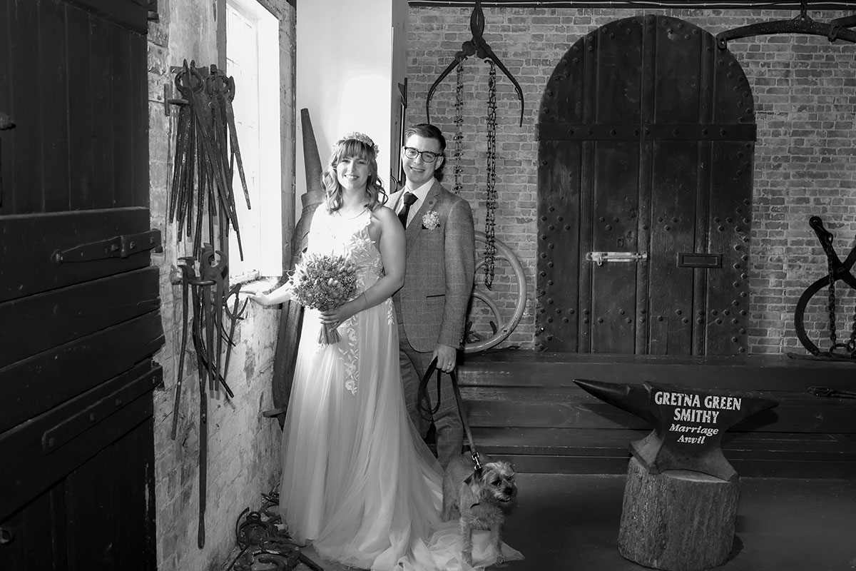 black and white picture of bride and groom with border terrier dog at gretna green