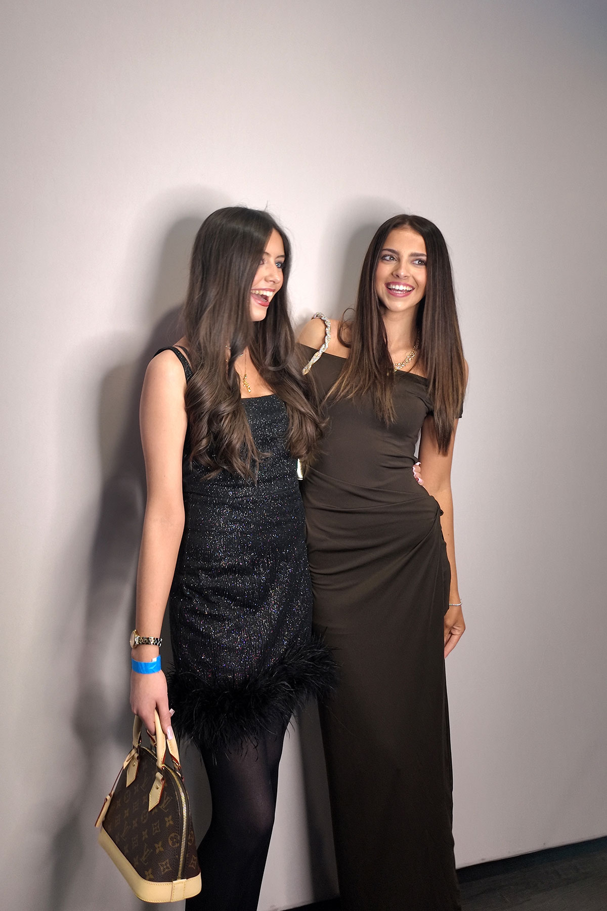Two women posing at event photo booth wearing evening dresses, smiling for professional photo booth portrait