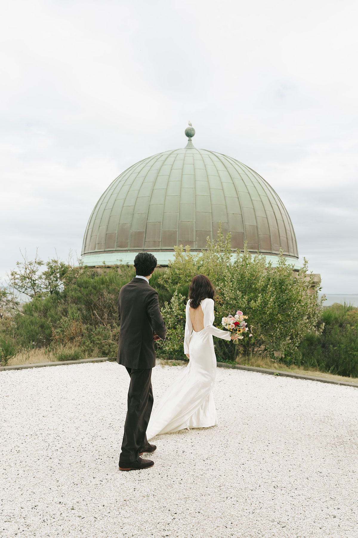 Bride and groom standing beneath the dome at the City Observatory on Calton Hill, Edinburgh.