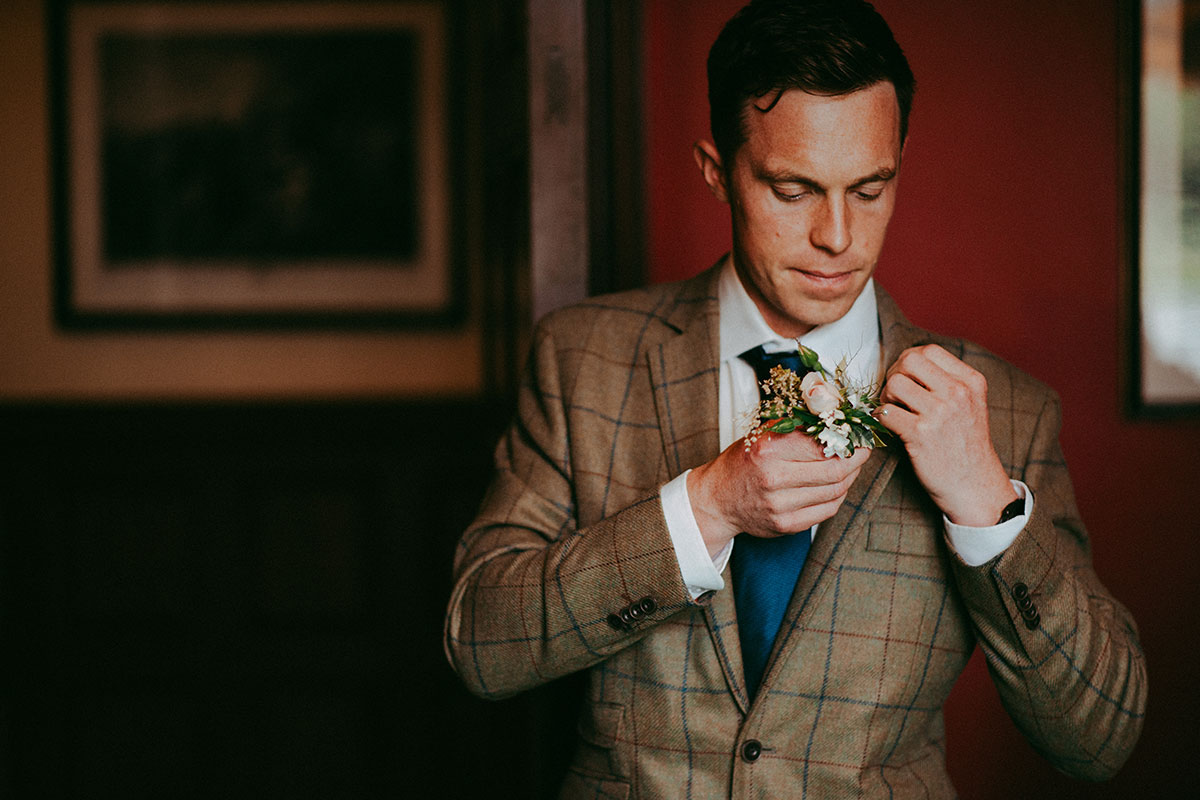 groom puts on flower buttonhole