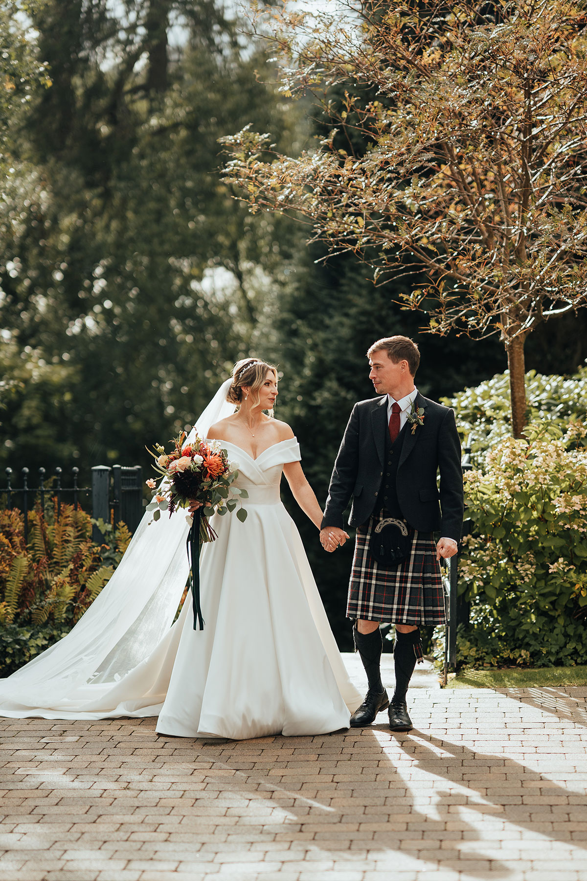 Bride and groom walking hand in hand through the gardens at Crossbasket Castle near Glasgow