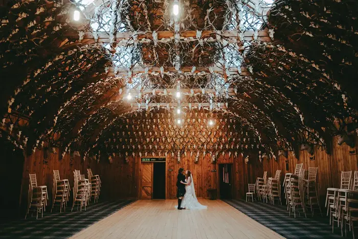 A bride and groom standing in the middle of a dancefloor in Mar Lodge Estate surrounded by stag heads on the wall