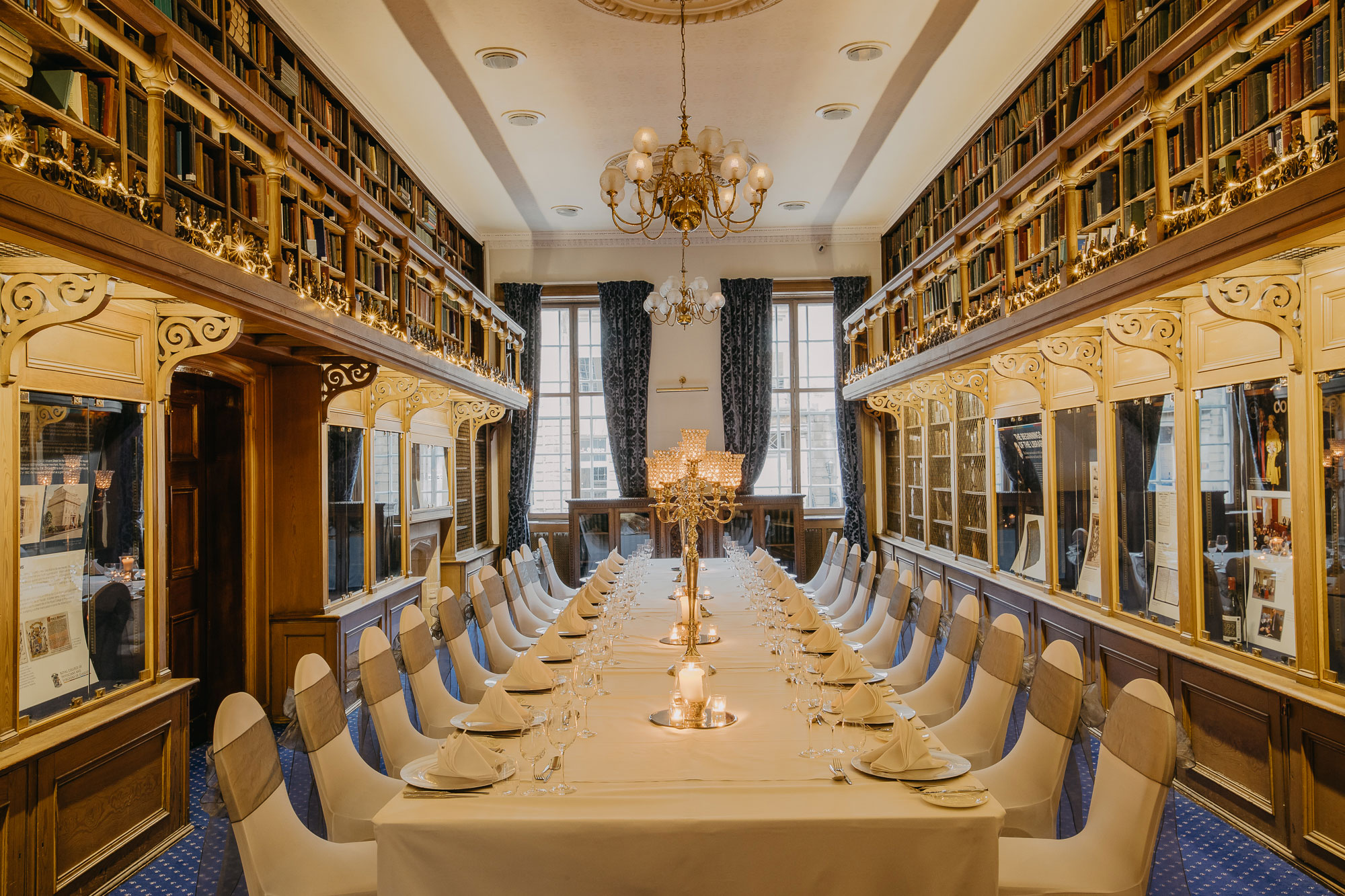the library inside 1599 at the royal college with large table and chairs set up for a wedding