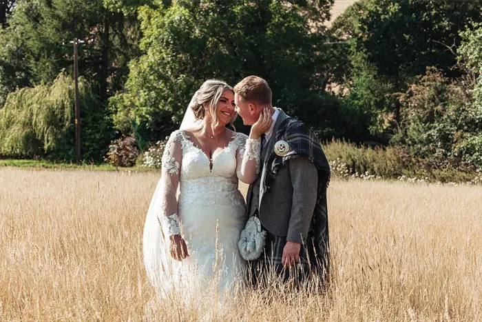 A bride and groom in a field at Enterkine House