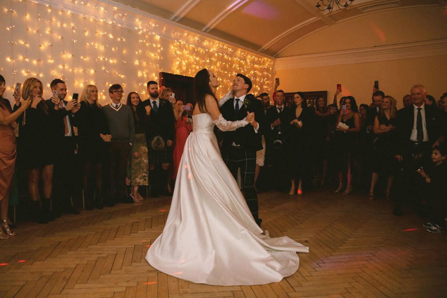 A Bride And Groom Dancing At A Wedding As Guests Look On