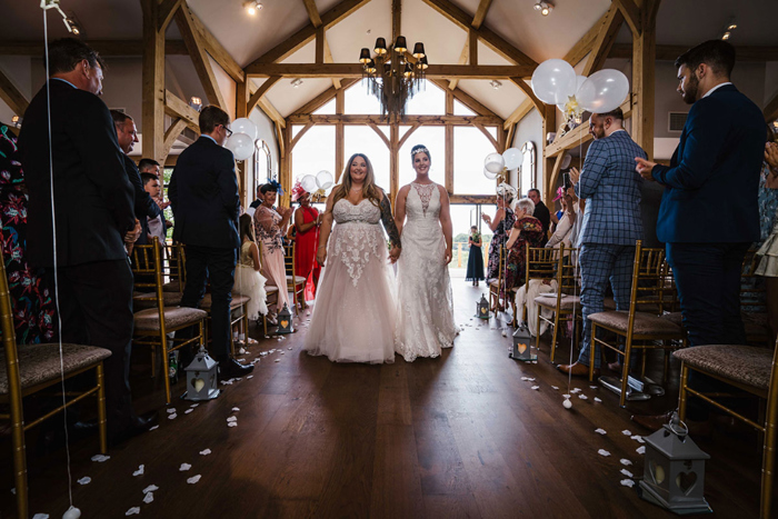 Two Brides Walking Back Up The Aisle During A Wedding Ceremony At Enterkine House