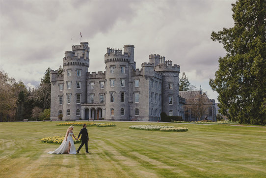 A bride and groom in front of a castle.