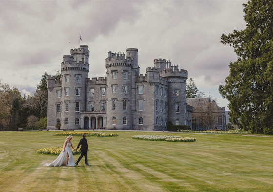 A bride and groom in front of a castle.