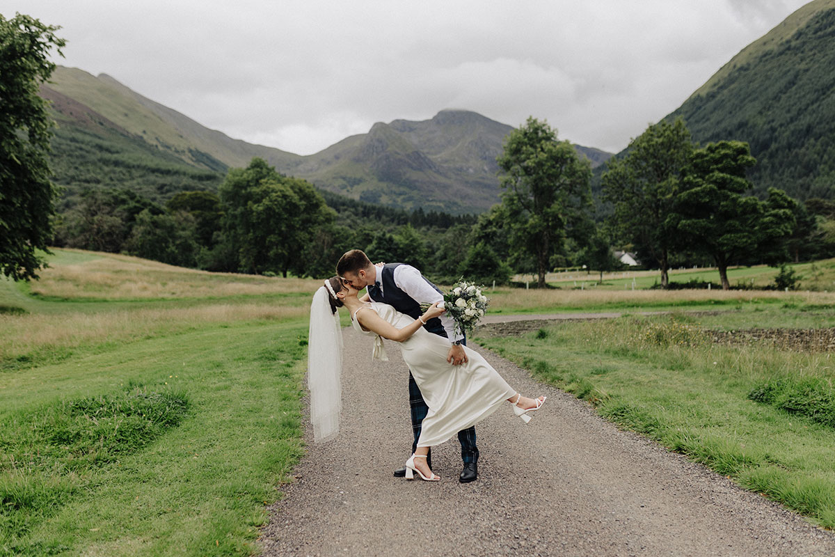 Groom dipping the bride in a kiss with Glencoe mountain backdrop