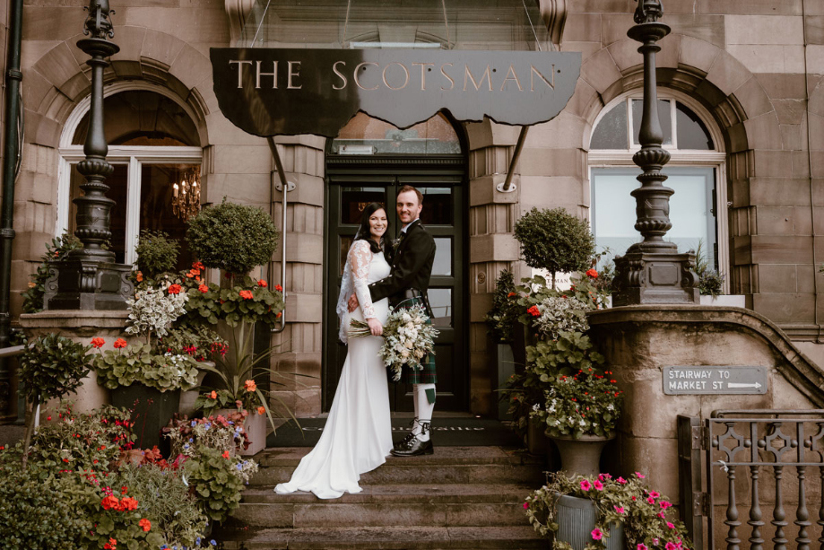 Couple pose under The Scotsman sign 