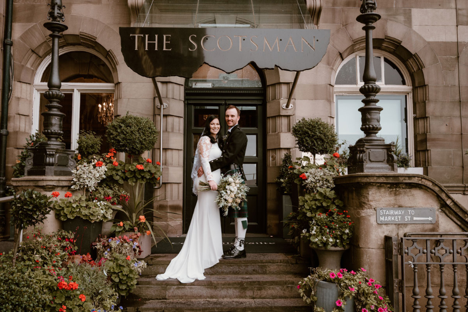 Couple pose under The Scotsman sign