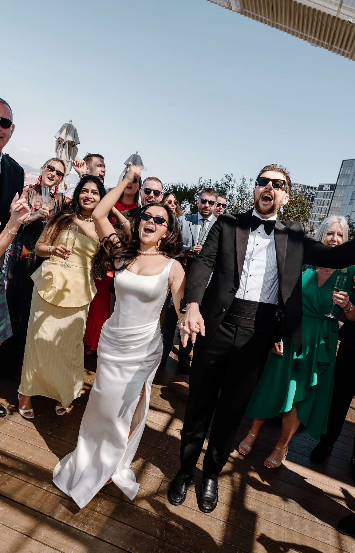 Bride and groom celebrate with friends and family during their sunny rooftop wedding reception at The Hoxton Barcelona.