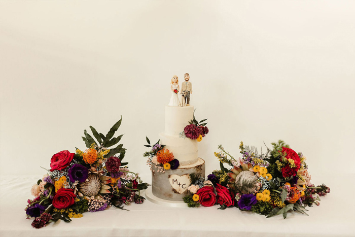 White wedding cake with colourful bouquets at the side 