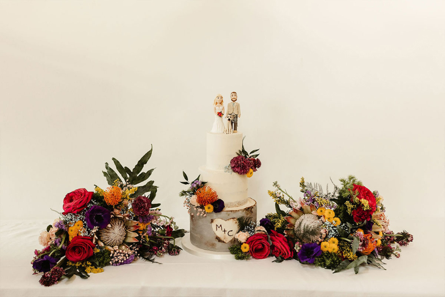 White wedding cake with colourful bouquets at the side