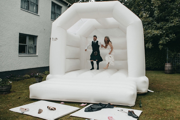Bride and groom jump on a white bouncy castle