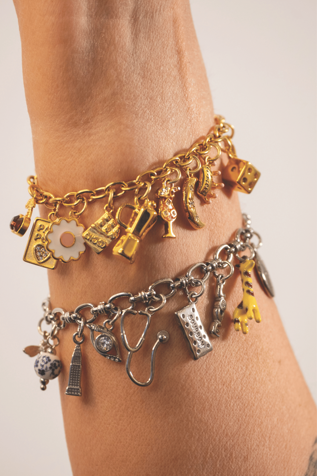 Close-up of gold and silver charm bracelets featuring playful personalised charms for wedding jewellery.