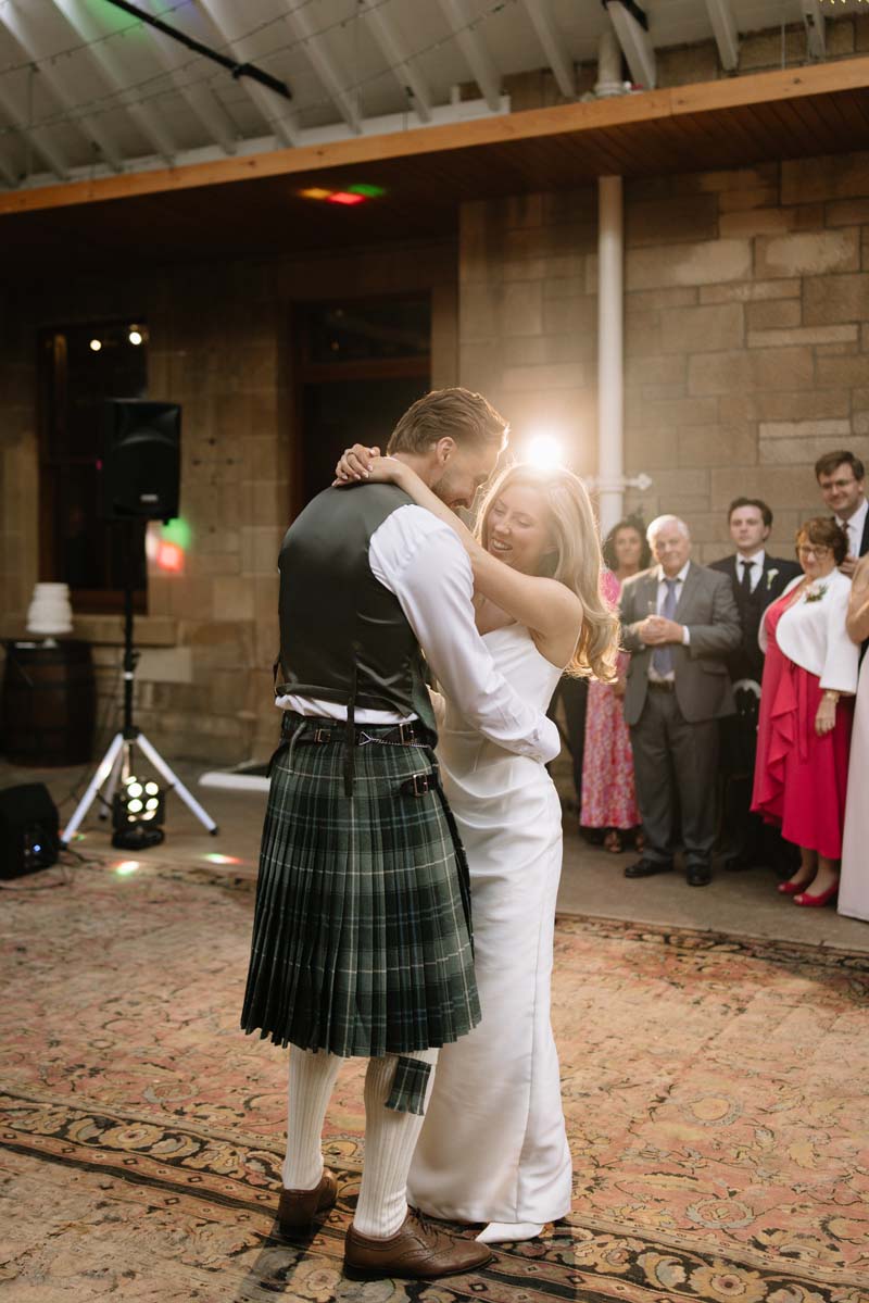 Lia and Louis share their first dance in the courtyard at Cambo House as wedding guests look on.