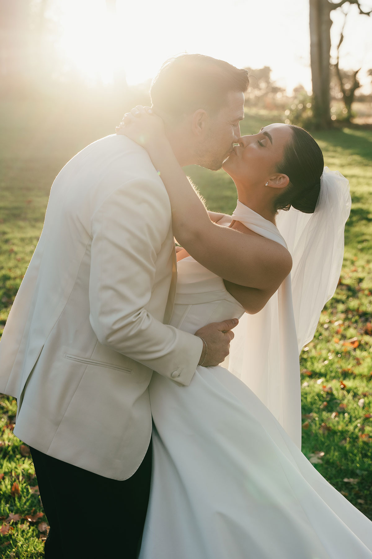 Bride and groom kissing in golden hour sunlight outdoors at Enterkine Country House wedding Ayrshire