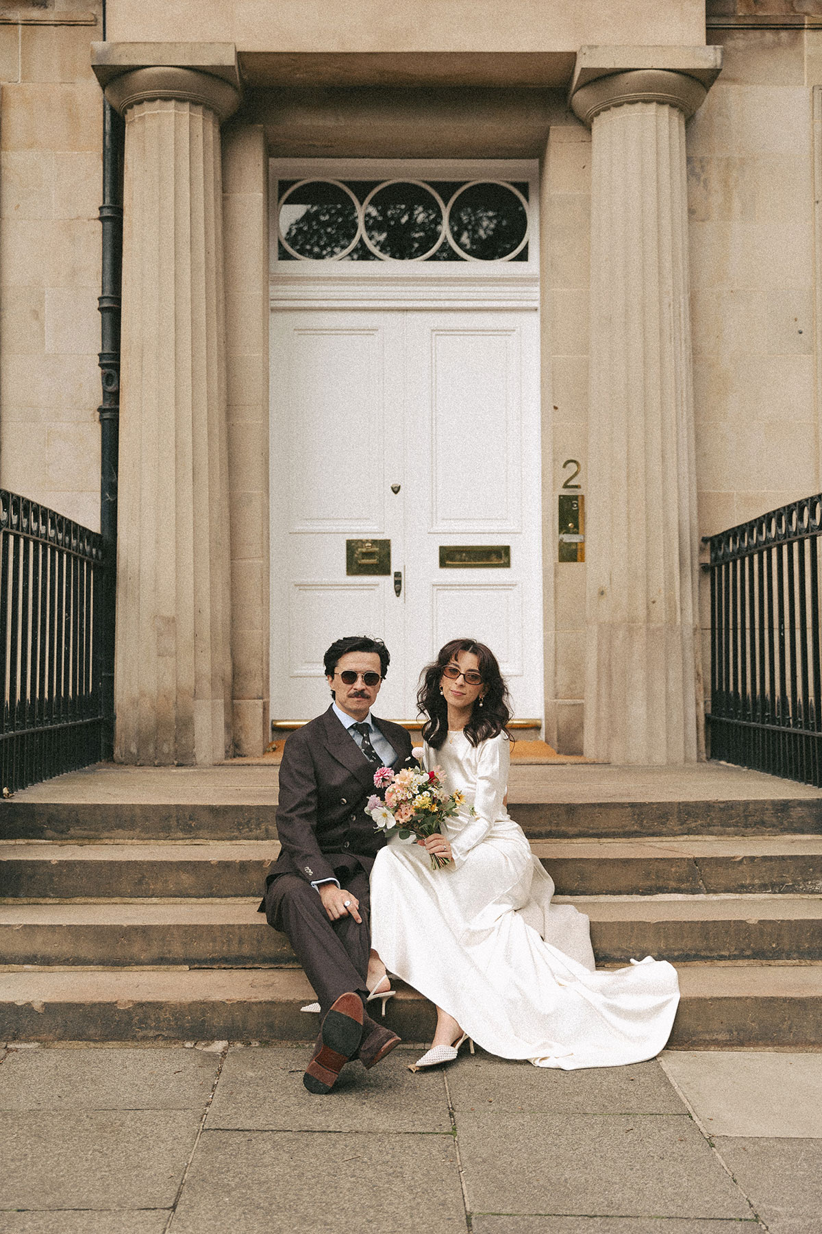 Newlyweds sitting on stone steps in Edinburgh New Town following their city wedding