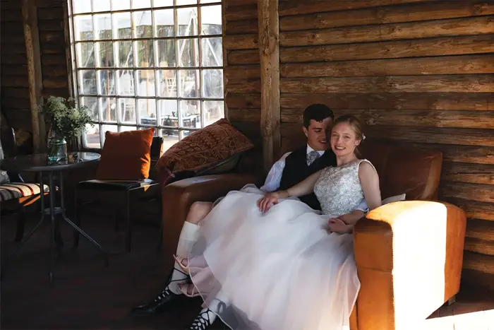 A bride and groom sitting on a couch inside a log cabin