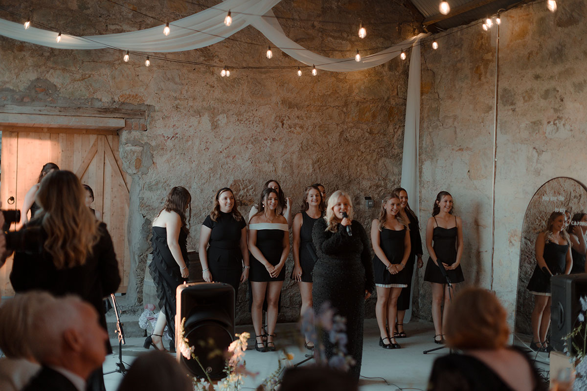 Surprise choir performing inside rustic barn during same-sex wedding on private farm near Falkirk
