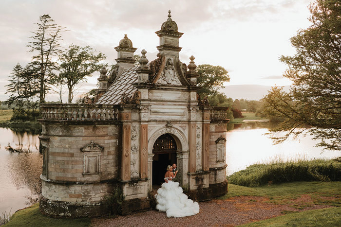 A bride in a wedding dress and groom in front of an ornate building