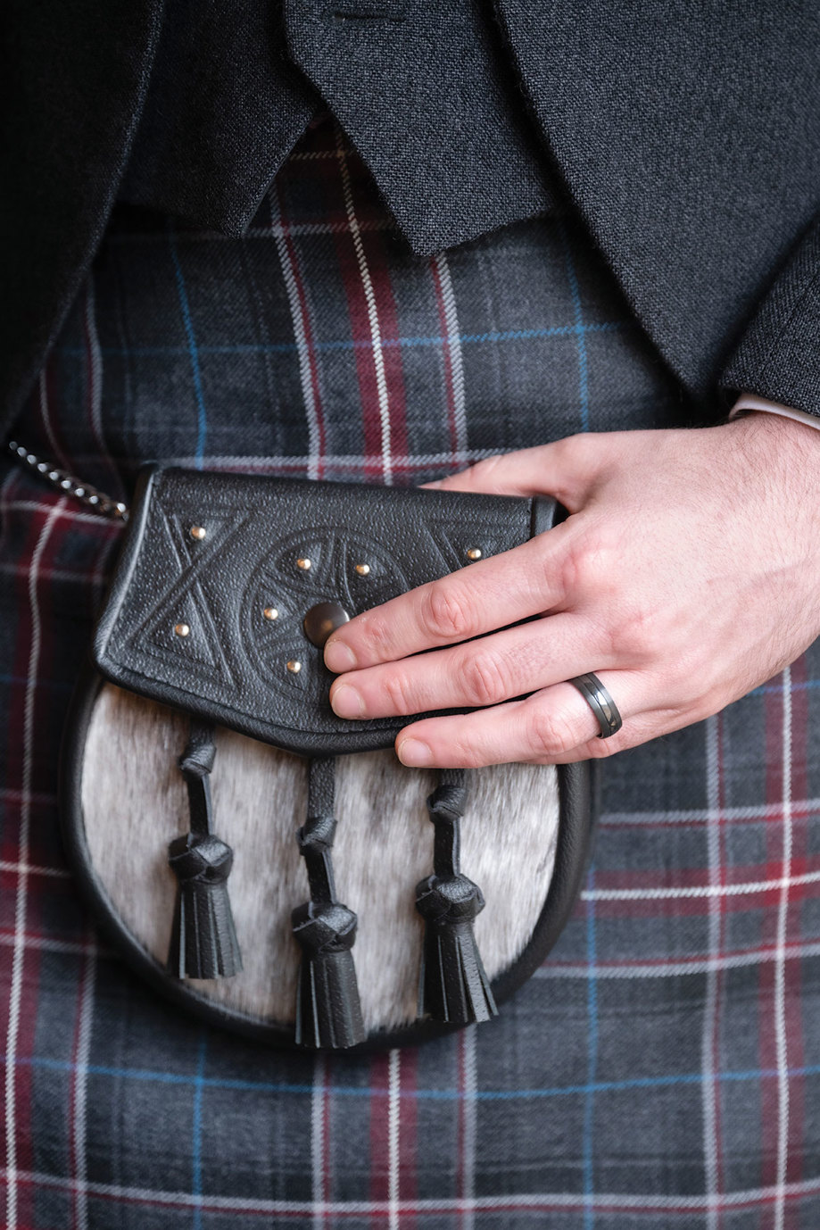 a hand on a black and grey sporran against a 1314 Bannockburn tartan kilt 