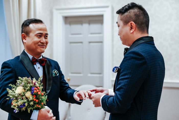 two grooms exchanging wedding rings