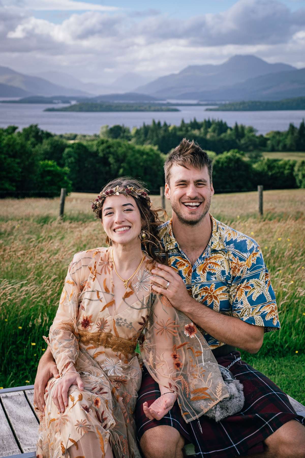 Smiling newlyweds posing in the grounds of Ardoch Loch Lomond with scenic loch views