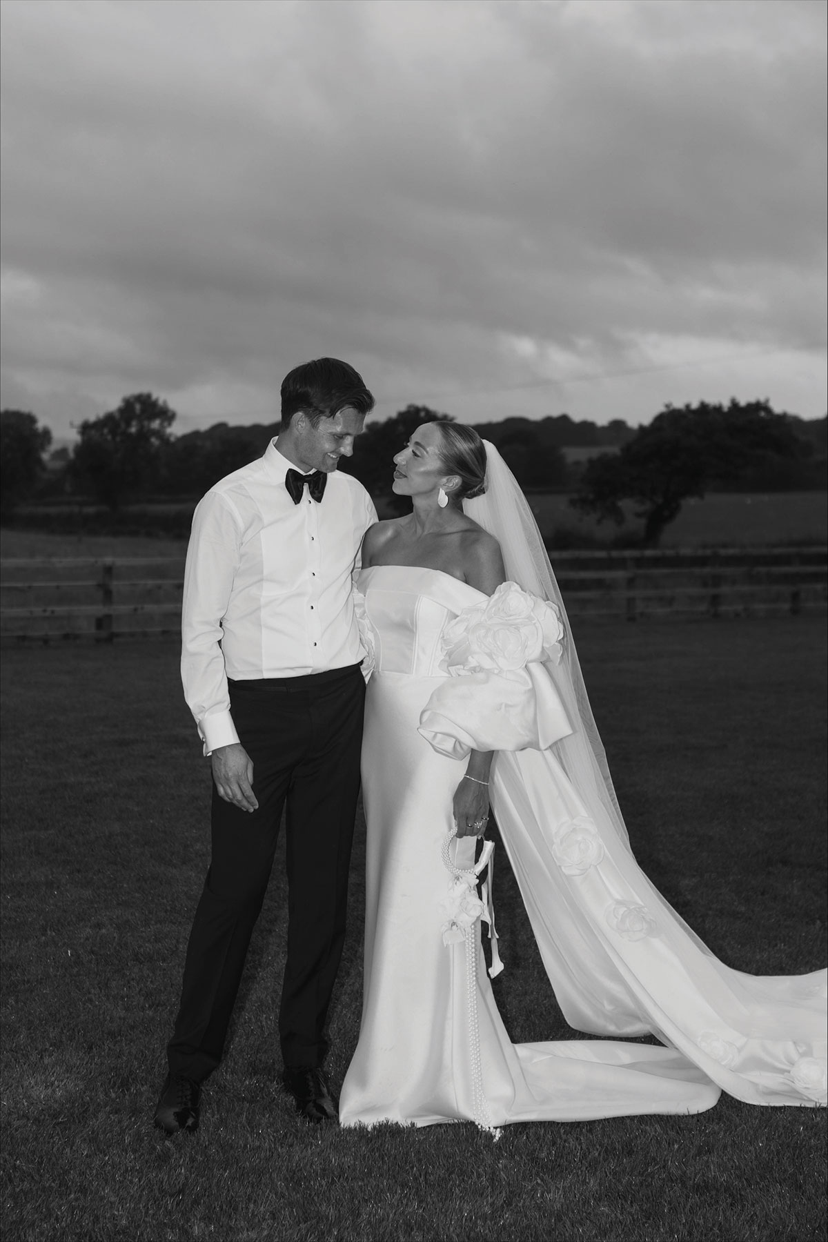 Black and white portrait of bride and groom standing together outdoors after their wedding.