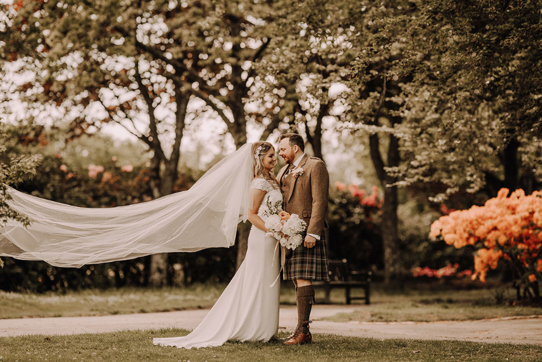 Newlywed portraits with bride's veil blowing in breeze