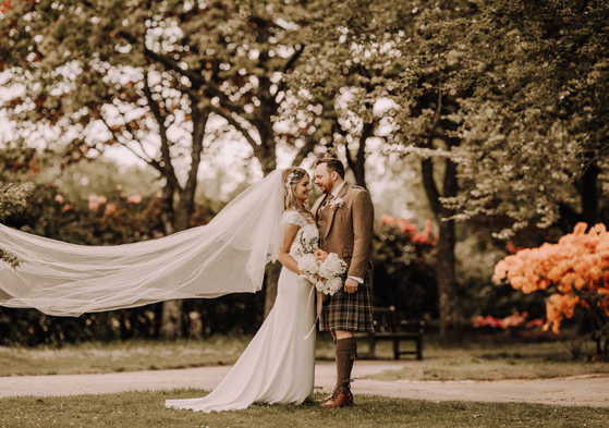 Newlywed portraits with bride's veil blowing in breeze