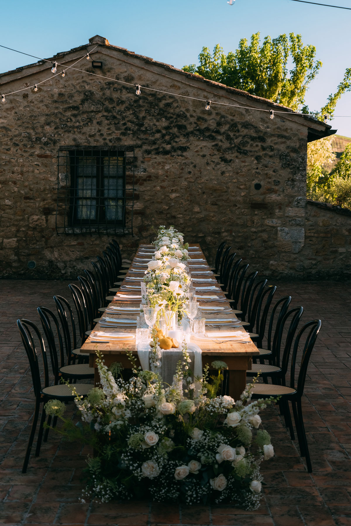 Long outdoor wedding table with white floral styling at Antico Borgo San Lorenzo Tuscany