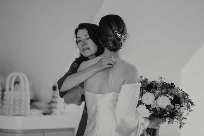 A Black And White Image Of A Lady Hugging A Bride