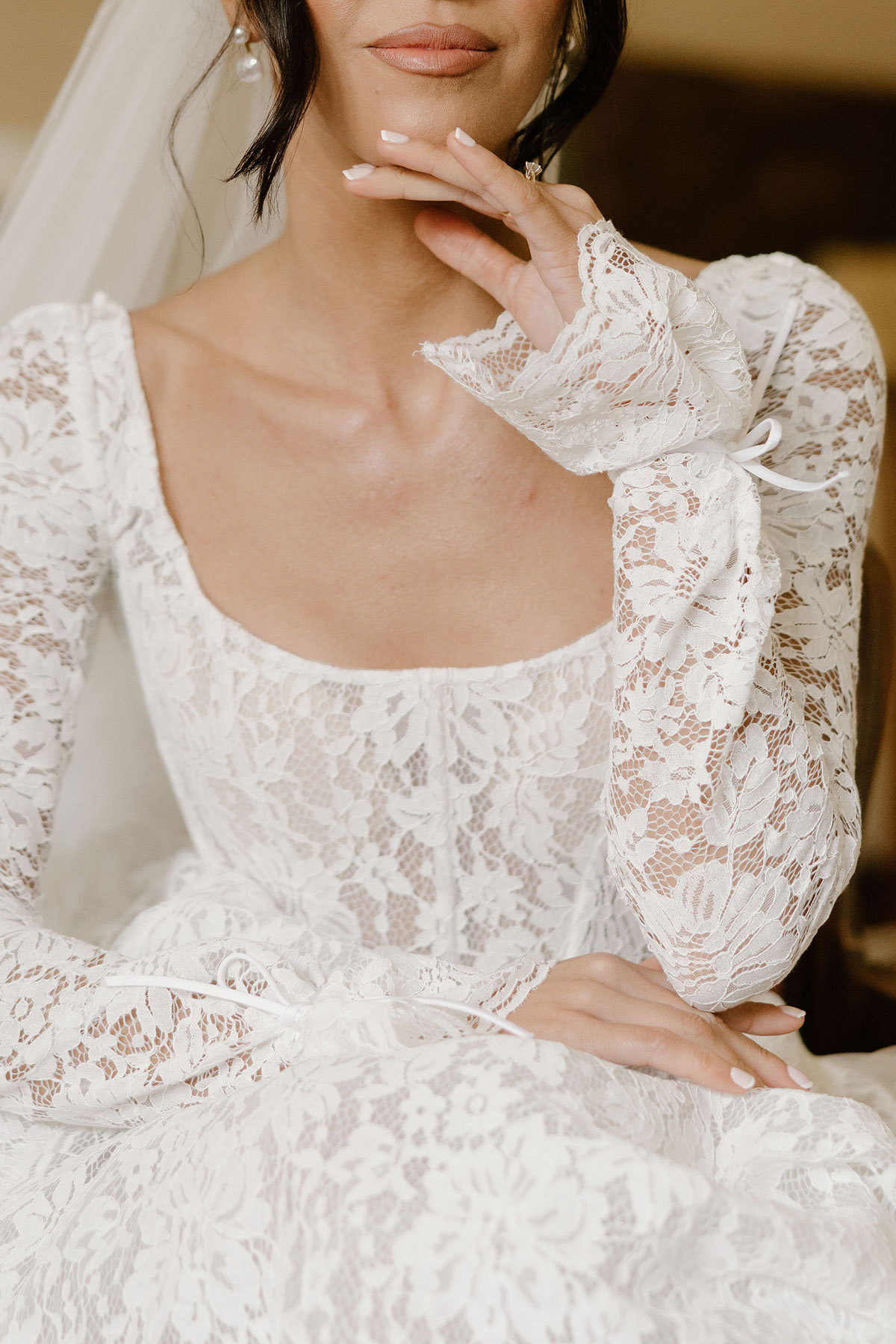 Close-up of a lace wedding dress bodice and sleeve with ribbon cuff details