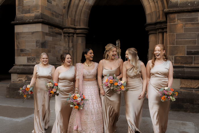 A Bride Wearing A Pink Lehenga And Four Bridesmaids Wearing Oyster Satin Dresses Walking At Glasgow University