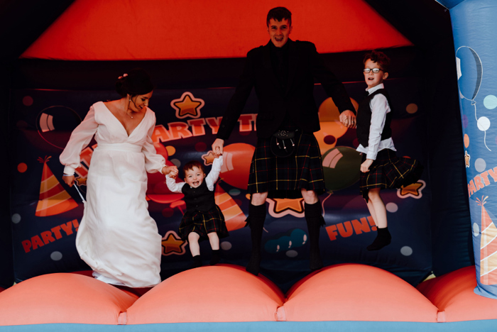 Bride and groom on bouncy castle with their children